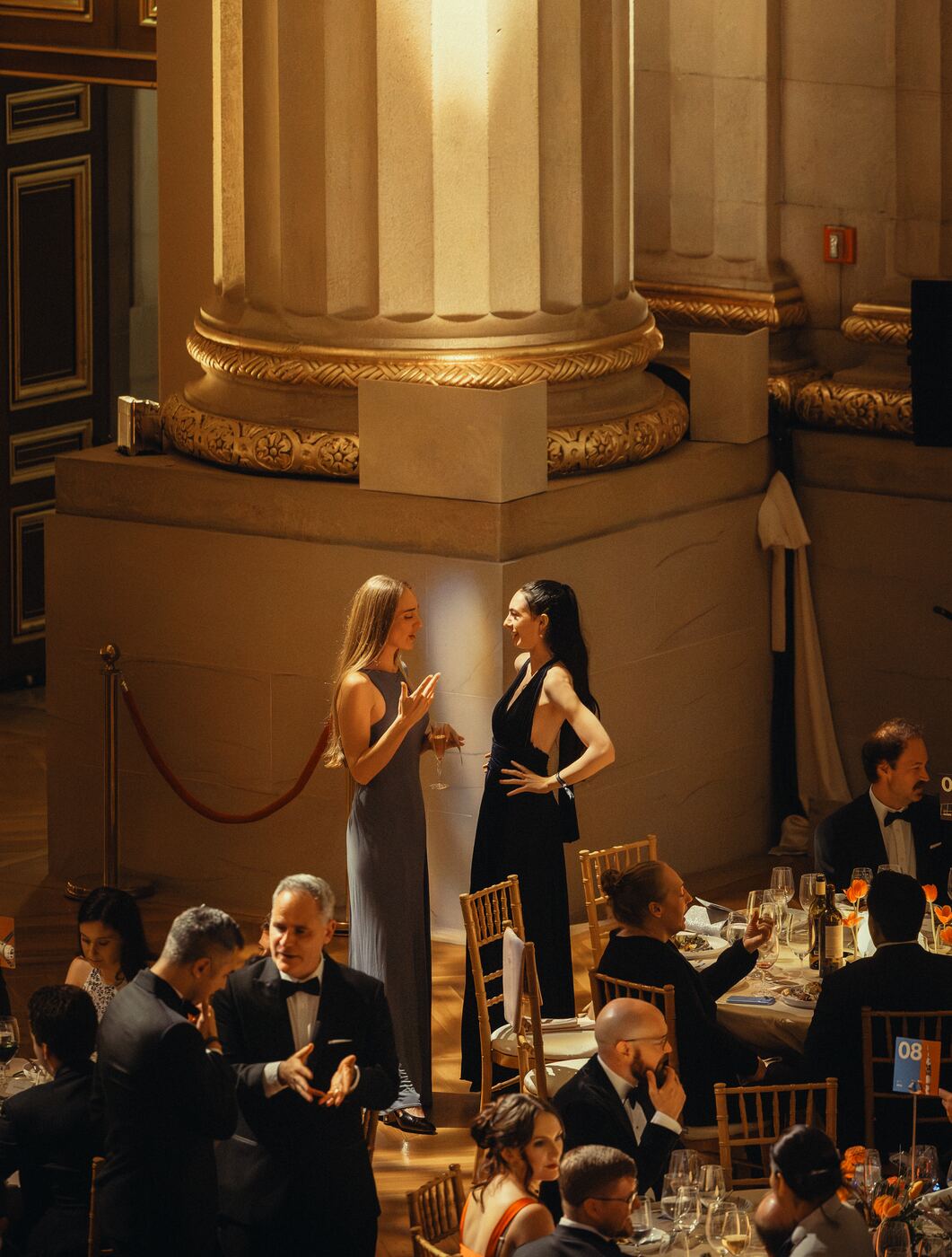 Guests at dinner beneath a gilded column
